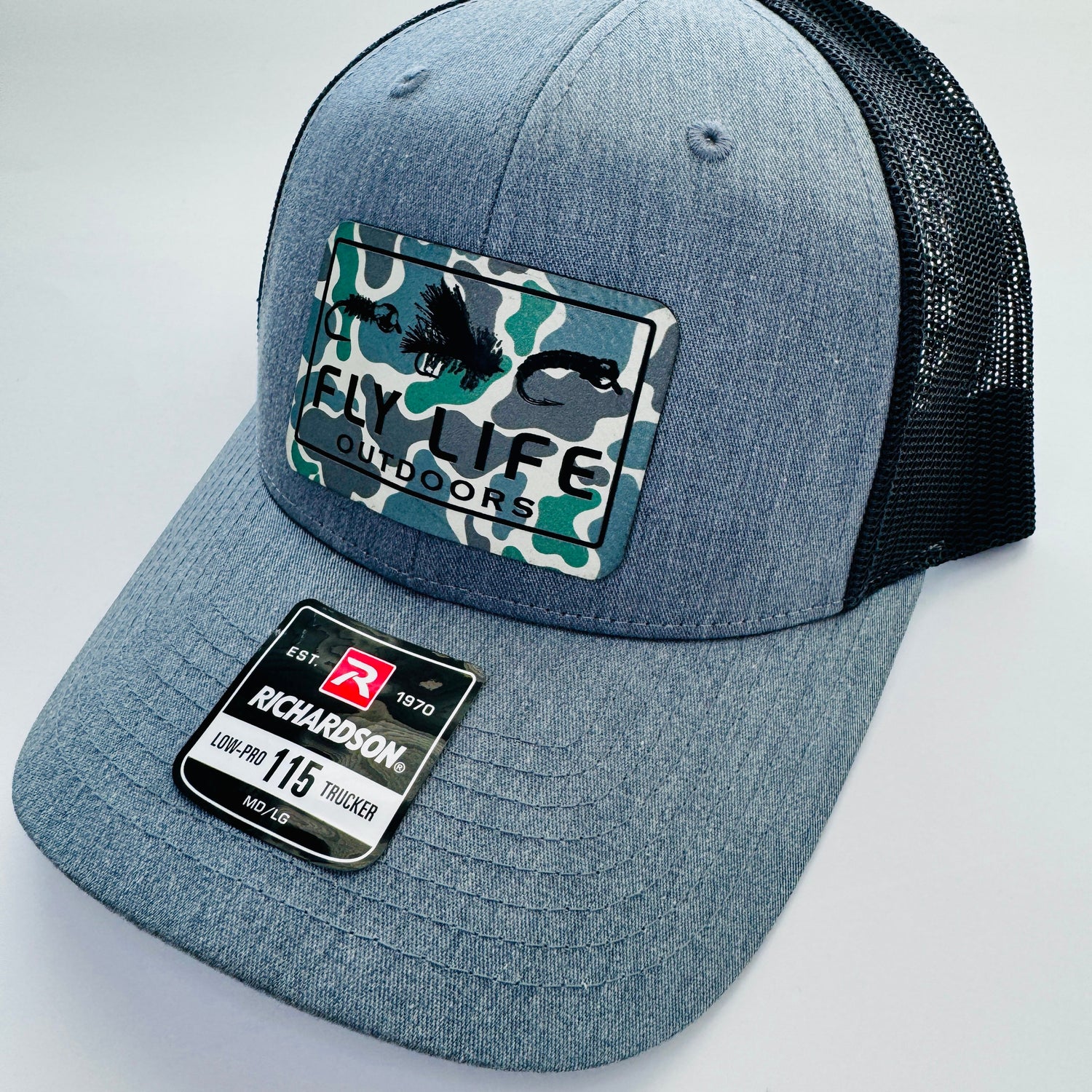 Right angle view of the FLO 115 Trucker Hat in Heather Grey/Black featuring a Fly Life Outdoors Low Tide Camo patch and Black Tri-Fly design