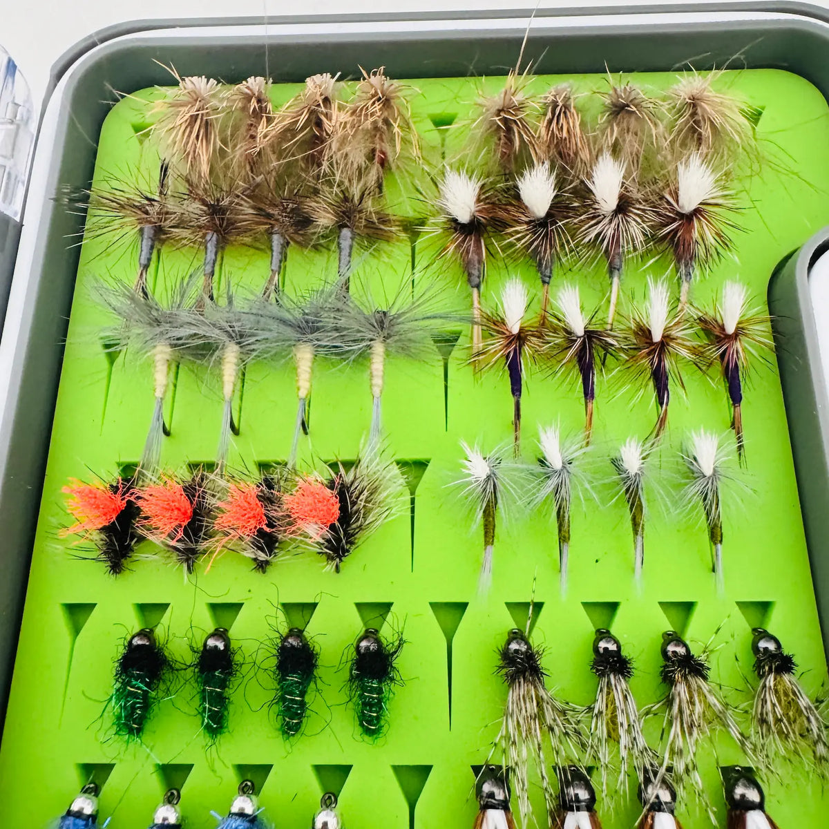 Close-up of All-Water Arsenal dry flies, including CDC Elk Hair Caddis, parachute mayflies, and orange-post Hi-Viz Griffith’s Gnats.