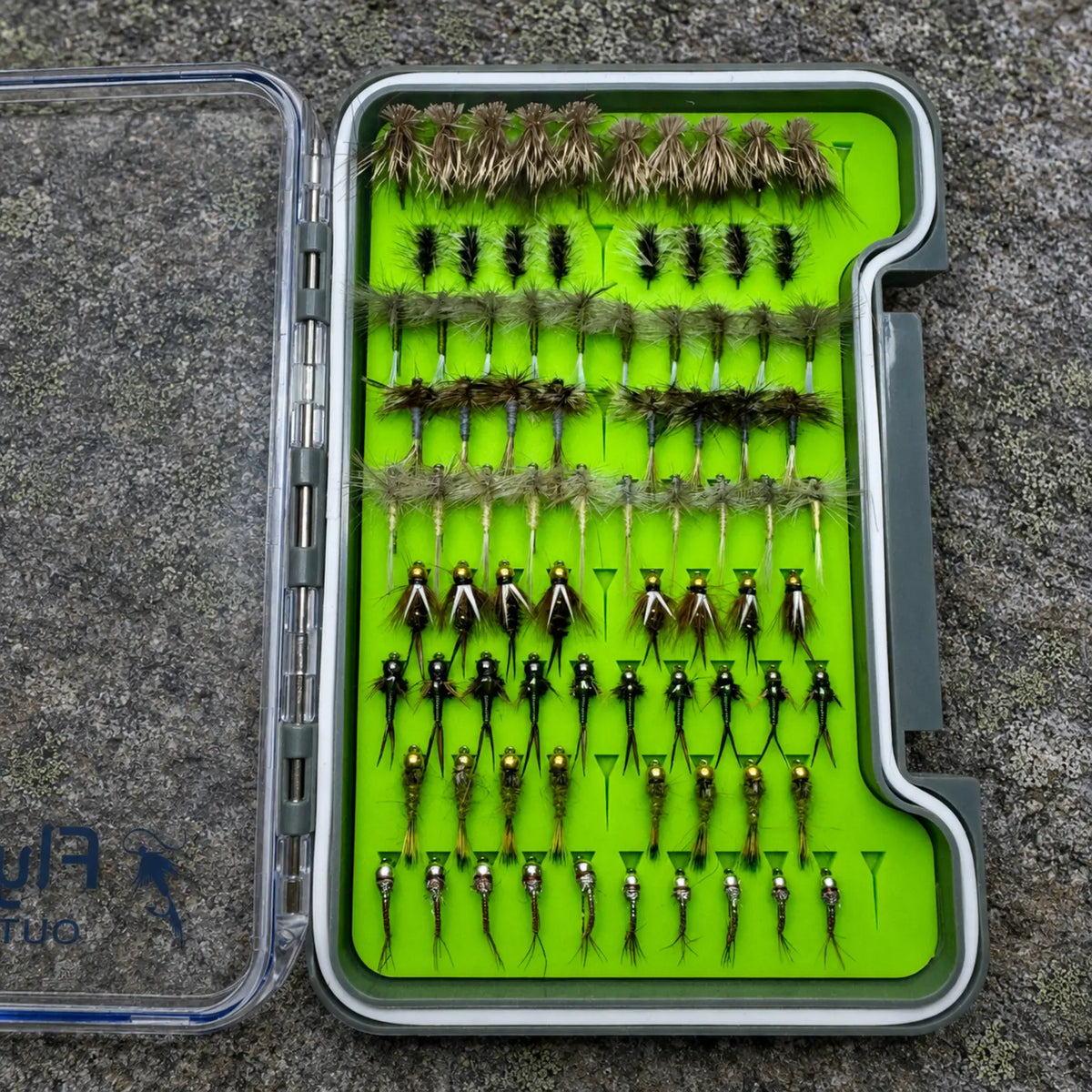 Essentials loaded fly box open overhead on river rock showing 82 hand-tied NC trout flies including Elk Hair Caddis, Griffith's Gnat, Copper Johns, and Rainbow Warriors