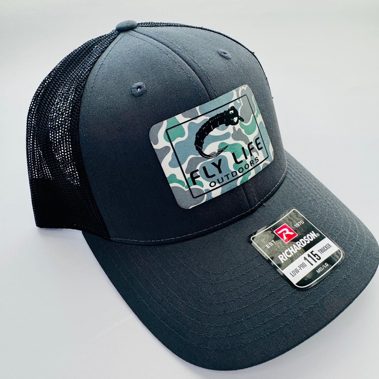 Left angle view of The FLO 115 Trucker in Charcoal with Black Midge/Low Tide Camo patch | Charcoal/Black
