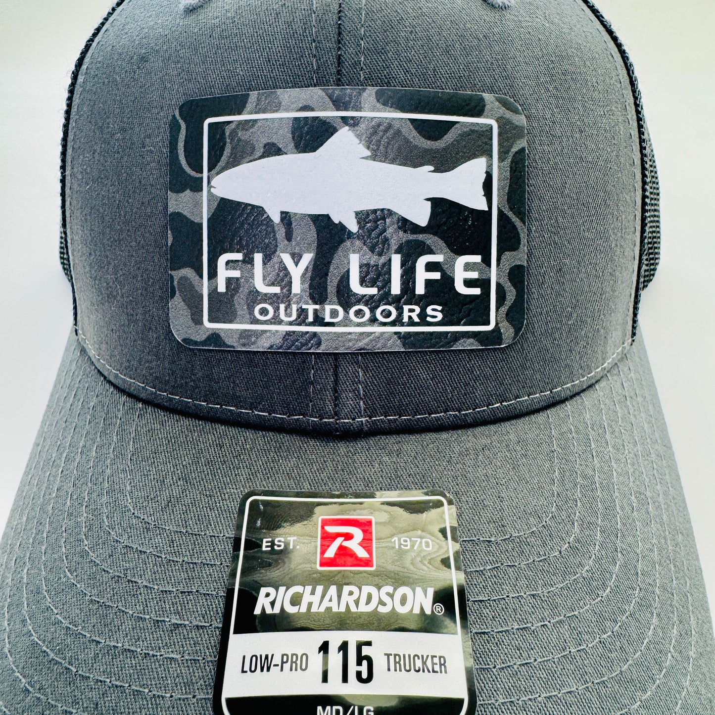 Close up view of The FLO 115 Trucker in Charcoal with White Trout/Black Skies Camo patch | Charcoal/Black