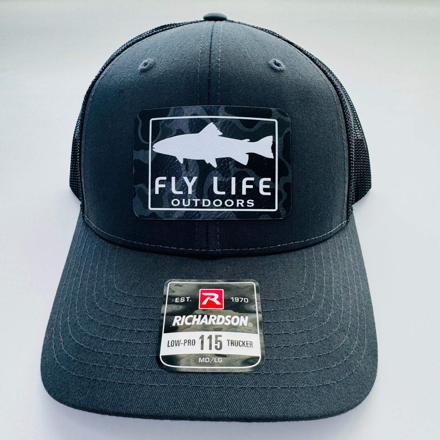 Front view of The FLO 115 Trucker in Charcoal with White Trout/Black Skies Camo patch | Charcoal/Black