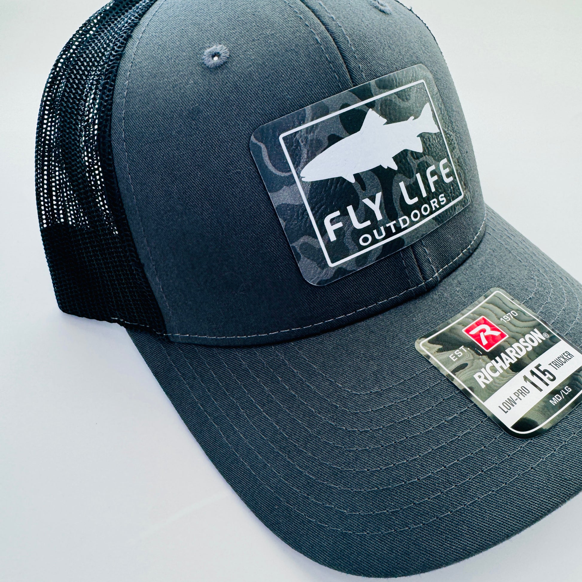 Left angle view of The FLO 115 Trucker in Charcoal with White Trout/Black Skies Camo patch | Charcoal/Black