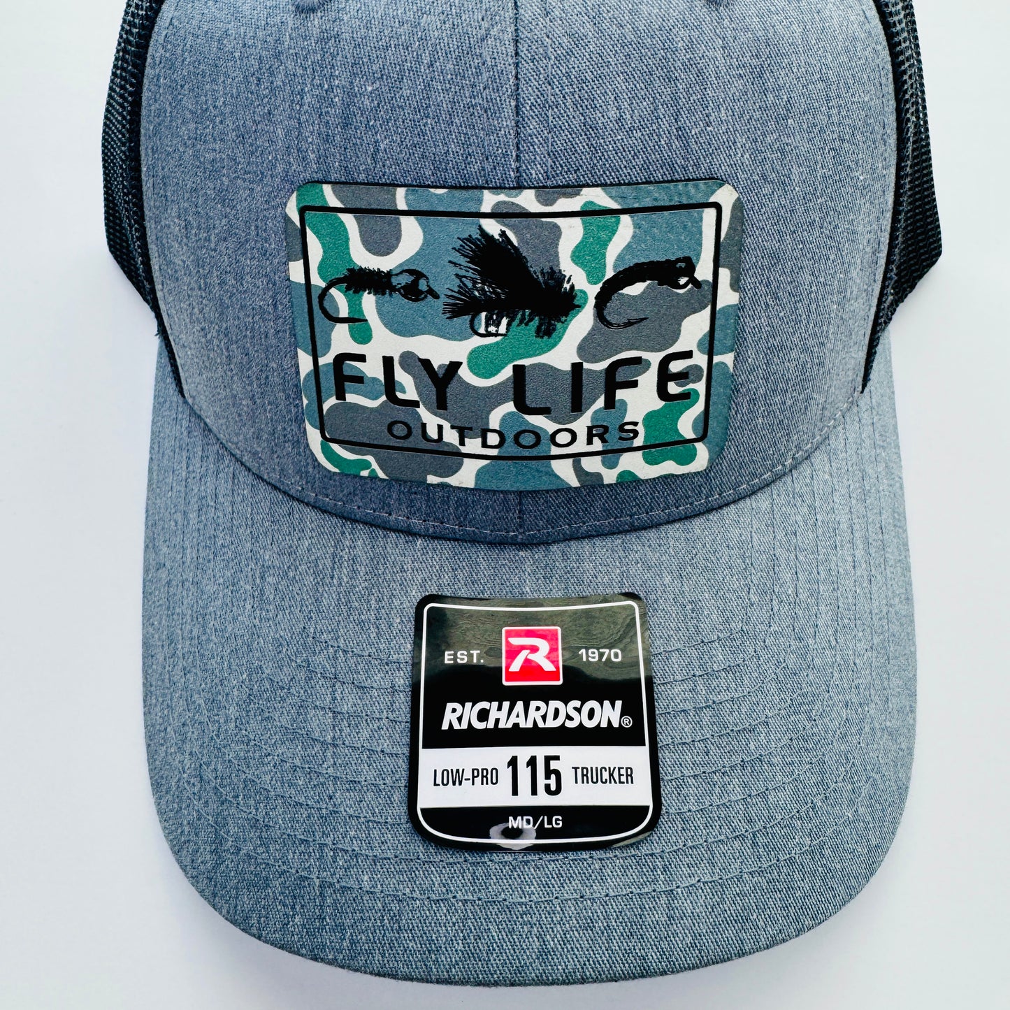 Close up view of the patch and bill of The FLO 115 Trucker in Heather with Black Tri-Fly/Low Tide Camo patch | Heather Grey/Black