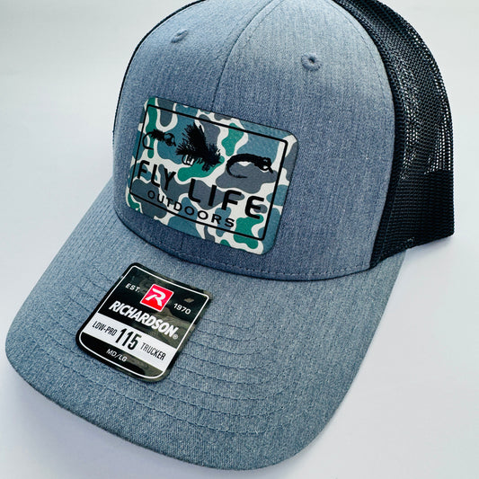 Right angle view of The FLO 115 Trucker in Heather with Black Tri-Fly/Low Tide Camo patch | Heather Grey/Black