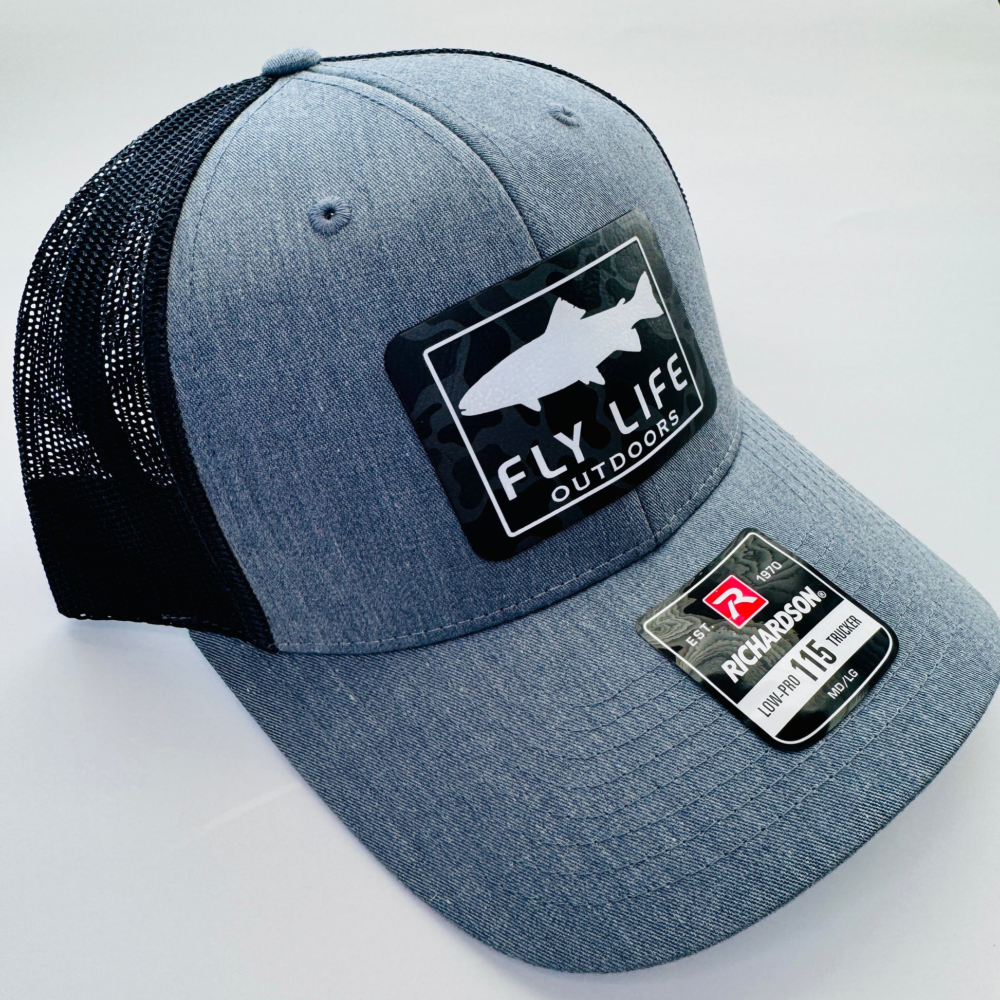 Left angle view of The FLO 115 Trucker in Heather Grey with White Trout/Black Skies Camo patch | Heather Grey/Black