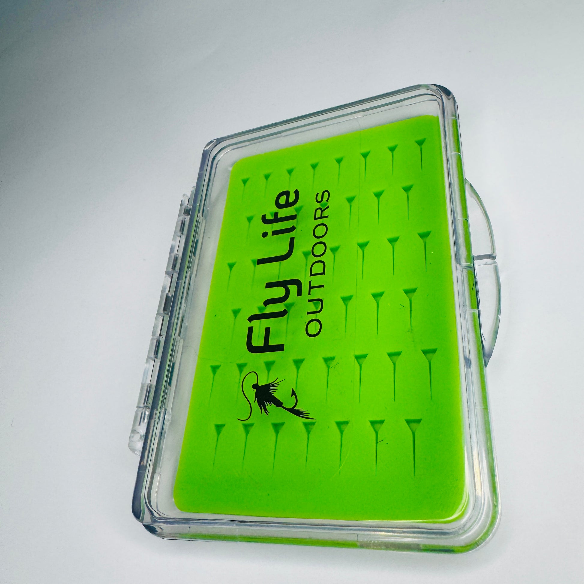 Angled view of The Outpost Slim Fly Box, highlighting its ultra-thin profile for easy pocket storage.