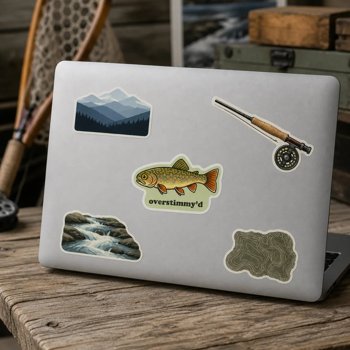 Overstimmy’d brook trout sticker on a laptop with fly-fishing, mountain, stream, and topographic decals